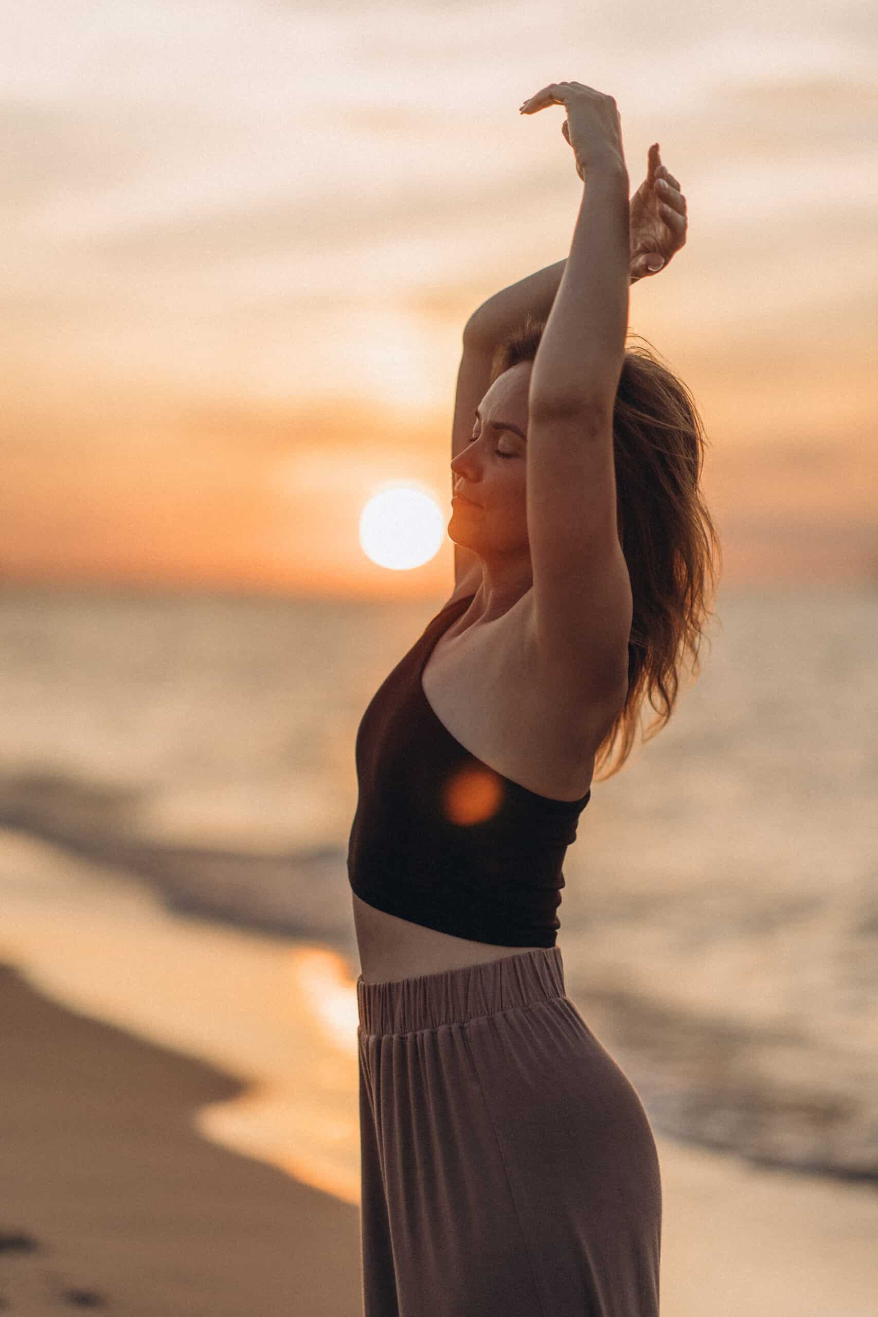 Kobieta wykonuje jogę na plaży podczas zachodu słońca, relaks i harmonia z naturą.